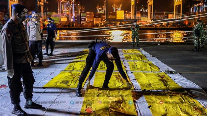 Anggota kepolisian mengangkat kantong jenazah berisi objek temuan dari lokasi jatuhnya pesawat Sriwijaya Air SJ 182 rute Jakarta-Pontianak pada hari keenam Operasi SAR pesawat tersebut di Dermaga JICT 2, Tanjung Priok, Jakarta Utara, Kamis (14/1/2021).
