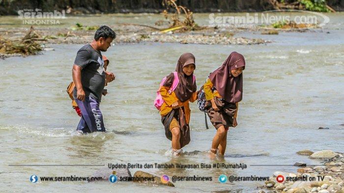 Pelajar harus menyeberangi sungai sebelum menuju ke sekolah mereka di Desa Panca Kubu, Kecamatan Lembah Seulawah, Aceh Besar, Jumat (22/1/2021).