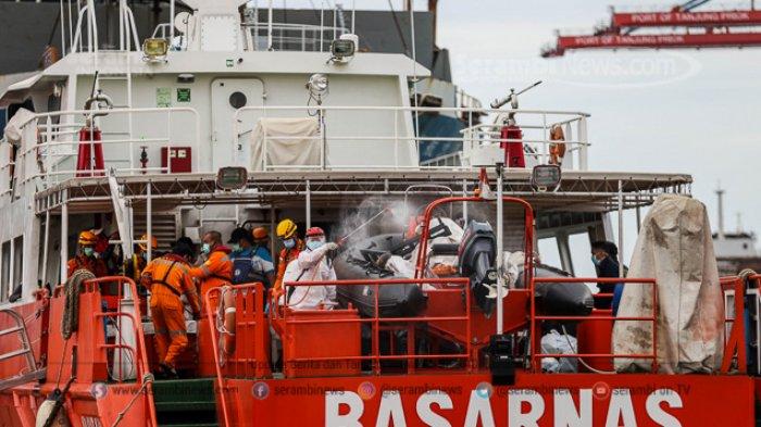 Petugas PMI menyemprotkan cairan disinfektan ke kantong jenazah berisi objek temuan dari lokasi jatuhnya pesawat Sriwijaya Air SJ 182 rute Jakarta-Pontianak pada hari keenam Operasi SAR pesawat tersebut di Dermaga JICT 2, Tanjung Priok, Jakarta Utara, Kamis (14/1/2021).