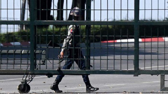 Seorang polisi berjalan di belakang area yang diblokir oleh gerbang dekat bandara internasional di Yangon pada 1 Februari 2021