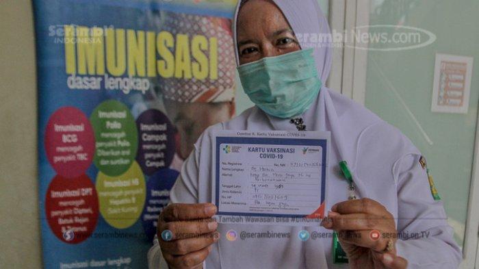 Seorang tenaga kesehatan menunjukan kartu vaksinasi covid-19 usai divaksin di Pukesmas Ingin Jaya, Aceh Besar, Senin (18/1/2021).