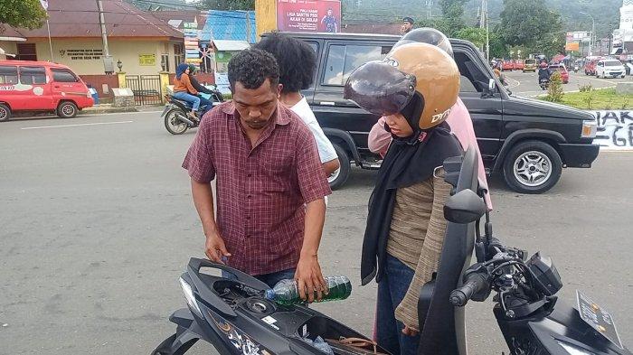Salah seorang mahasiswa mengisi Pertalite pengendara dalam aksi berbagi BBM di Bundaran Poka - Ambon, Senin (18/4/2022)