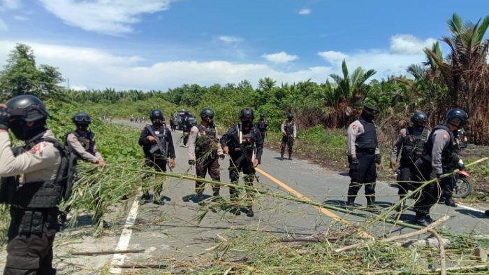 Aparat Brimob Polda Maluku yang bertugas mengamankan perhelatan Pekan Olahraga Nasional (PON) XX di Papua, membantu membuka akses jalan yang ditutup warga adat setempat, Selasa (21/9/2021).
