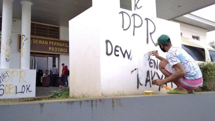 Seorang petugas kebersihkan mengecat coretan pada bagian pilar gedung Kantor DPRD Maluku