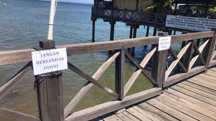 Dispar Buleleng saat memasang papan imbauan agar pengunjung tidak bersandar pada pembatas dermaga eks Pelabuhan Buleleng
