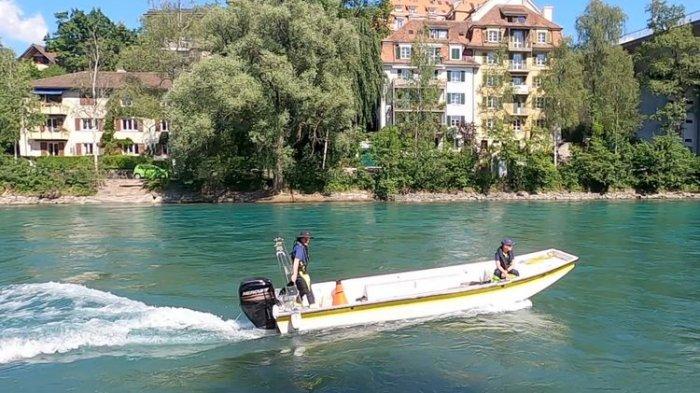 Dua petugas polisi Bern tengah berpatroli menggunakan kapal di sekitar Schoenausteg, Sungai Aare, Bern, Siwss pada Selasa (31/5/2022).