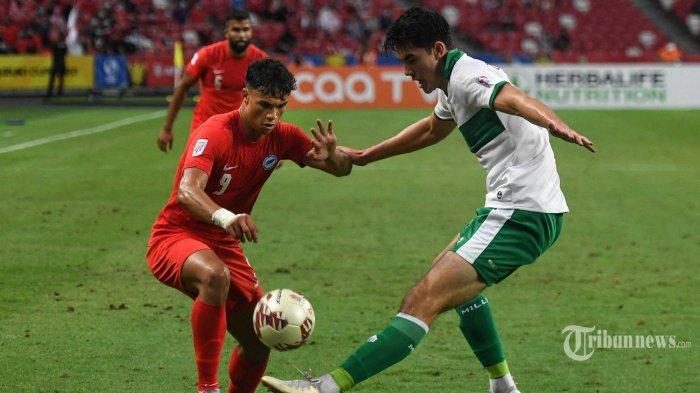 Pemain Singapura Ikhsan Fandi (kiri) berebut bola dengan pemain Timnas Indonesia Elkan William Tio Baggot pada pertandingan leg pertama semifinal sepak bola AFF Suzuki Cup 2020 antara Singapura dan Indonesia di National Stadium, Singapura, Rabu (22/12/2021) Hingga Peluit Panjang Berakhir Singapura berhasil menahan imbang Indonesia 1-1. (Roslan RAHMAN/AFP)