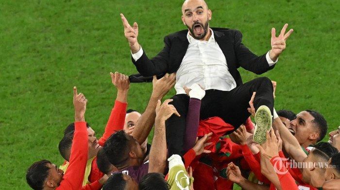 Para pemain Maroko melempar pelatih Maroko Walid Reragui ke udara saat mereka merayakan akhir pertandingan sepak bola babak 16 besar Piala Dunia Qatar 2022 antara Maroko dan Spanyol di Education City Stadium di Al-Rayyan, sebelah barat Doha. Selasa (6 Desember 2022). Glyn KIRK / AFP