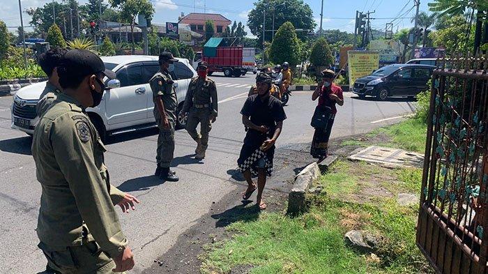 Nengah Bayung (21) bersama rekannya Nengah Hendra saat diamankan Satpol PP Kota Denpasar di perempatan Tohpati, Denpasar, Sabtu 25 September 2021 kemarin.