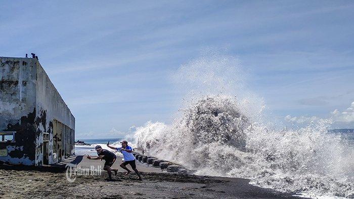 Warga berlari, setelah melakukan foro selfie dengan latar belakang ombak tinggi di lokasi proyek PPI di pantai Karangdadi, Desa Kusamba, Klungkung, Minggu (31/3/2019). Tingginya deburan ombak di lokasi itu menjadi daya tarik warga untuk berkunjung. Tinggi deburan ombak bahkan mencapai lebih dari 5 meter.