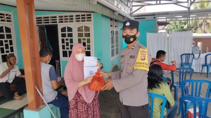 Bhabinkamtibmas Kelurahan Tuatunu Indah, Aipda Belly Marison saat memberikan bingkisan sembako kepada masyarakat yang telah mau melaksanakan vaksin Covid-19 di RT 7 Kelurahan Tuatunu Indah, Jumat (29/12/2021).