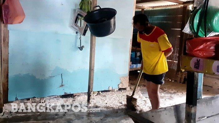 Usul (42) saat membersihkan pasir pantai yang masuk rumah warga sekitaran pantai Pasir Padi Pangkalpinang