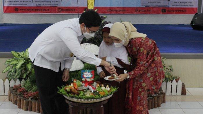 Pemotongan nasi tumpeng oleh Bupati HST dan Ketua TP PKK HST bersama perwakilan anak.
