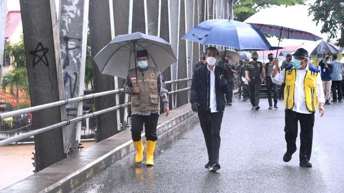 Gubernur Kalimantan Selatan, H Sahbirin Noor, Presiden Joko Widodo dan Menteri PUPR Basuki Hadimuljono, di bawah guyuran hujan meninjau kerusakan Jembatan Salim di Jalan A Yani Km 55, Kecamatan Mataraman, Kabupaten Banjar, yang ia tinjau saat kunjungan ke Kalsel, Senin (18/1/2021) siang.