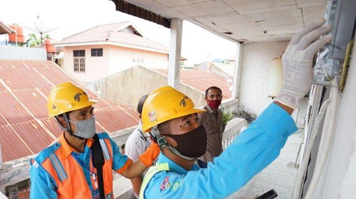 Petugas memeriksa meteran listrik pelanggan PLN.