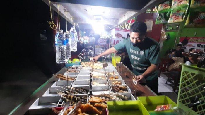 Ismail Saleh (34), pemilik Angkringan 'Mas Coy' tampak sedang sibuk melayani pesanan para pelanggannya.