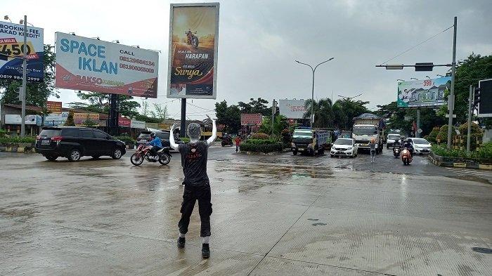 Manusia silver mengatur lalu lintas kendaraan di persimpangan lampu merah Jalan Lingkar Selatan (JLS) Kota Cilegon, Sabtu (3/4/2021). Lampu merah di persimpangan jalan tersebut mati setelah tersambar petir pada Jumat malam.