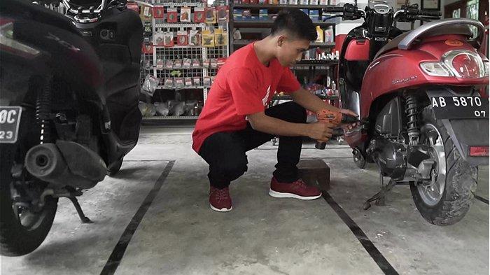 Ikbal Usman Febriyanto pemilik bengkel MAN Motor Kulonprogo, Yogyakarta yang merupakan binaan Yayasan AHM sedang melakukan perbaikan salah satu sepeda motor milik konsumen.