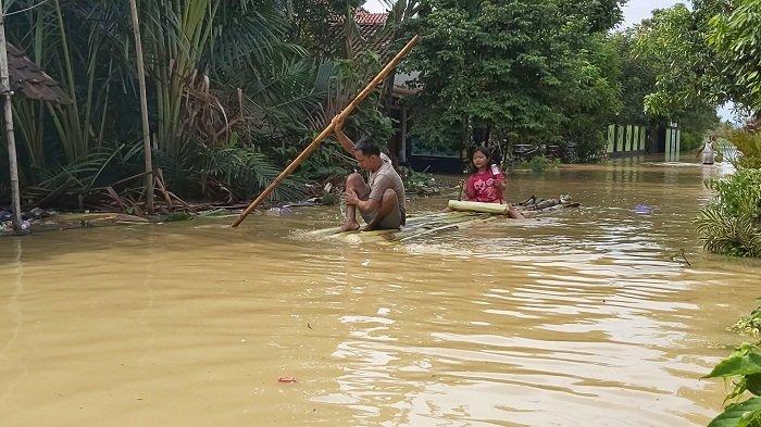 Warga membuat rakit dari pohon pisang untuk menembus banjir di Desa Gebangkerep, Kabupaten Pekalongan, Jawa Tengah, Minggu (6/2/2022).