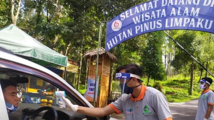 Petugas mengecek suhu tubuh pengunjung tempat wisata Hutan Pinus Limpakuwus, Banyumas, Sabtu (6/12/2020).