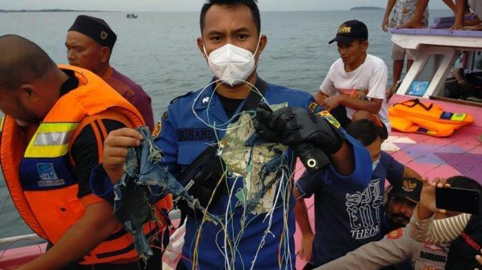 Petugas menunjukkan serpihan barang-barang di lokasi jatuhnya Sriwijaya Air