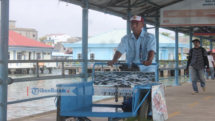 Suparmo sedang menyahuhkan becaknya di Pelabuhan Sri Bintan Pura