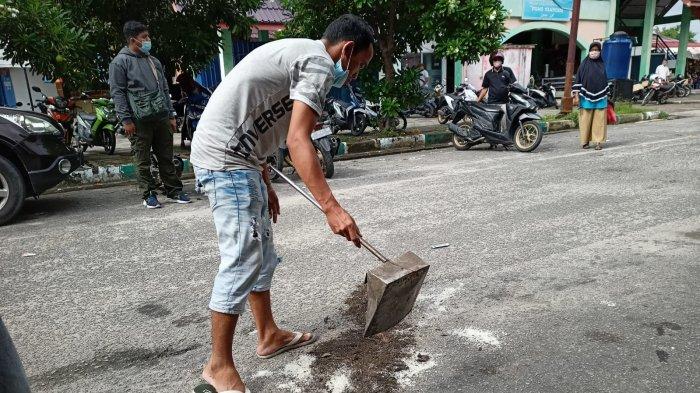 Warga Karimun menutupi bekas darah tempat wanita paruh baya terjun dari lantai tiga ruko dekat Pasar Puan Maimun, Selasa (17/8/2021).