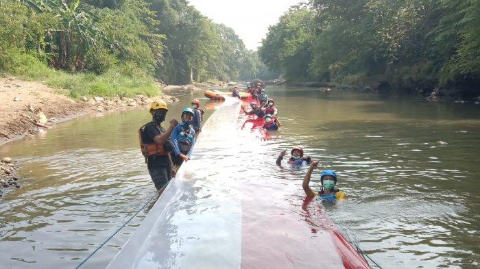 Bendera Merah Putih sepanjang 33 meter dibentangkan di atas aliran Kali Ciliwung di Kelurahan Cibuluh, Kecamatan Bogor Utara, Kota Bogor, Selasa (17/8/2021).
