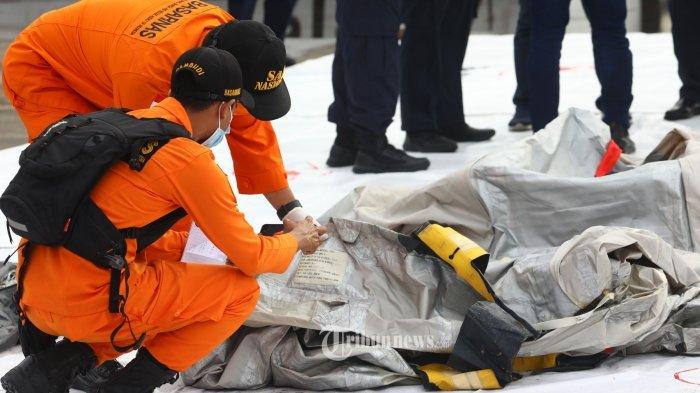 Petugas Basarnas memeriksa benda yang diduga serpihan dari pesawat Sriwijaya Air SJ 182 rute Jakarta - Pontianak yang hilang kontak di perairan Pulau Seribu, di Dermaga JICT, Jakarta, Minggu (10/1/2021). Pesawat Sriwijaya Air SJ 182 yang hilang kontak pada Sabtu (9/1) sekitar pukul 14.40 WIB di ketinggian 10 ribu kaki tersebut membawa enam awak dan 56 penumpang.