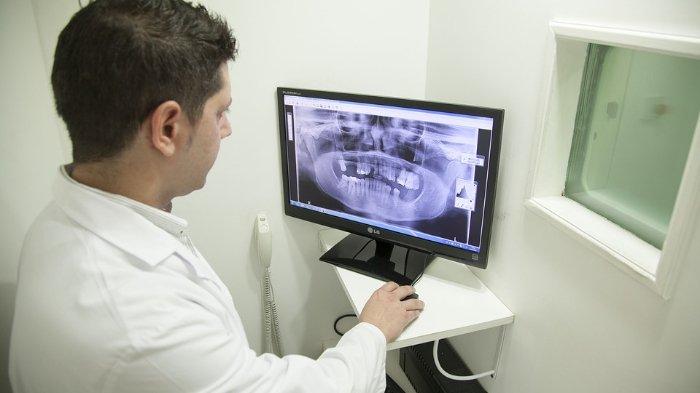 ilustrasi dokter gigi sedang memeriksa hasil rontgen panoramic