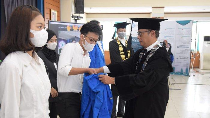 Wakil Ketua I Bidang Akademik, Kemahasiswaan, dan Alumni Dr. Ir. Dani Dagustani, MM., memakaikan jas almamater kepada perwakilan mahasiswa sebagai prosesi dalam PKKMB.