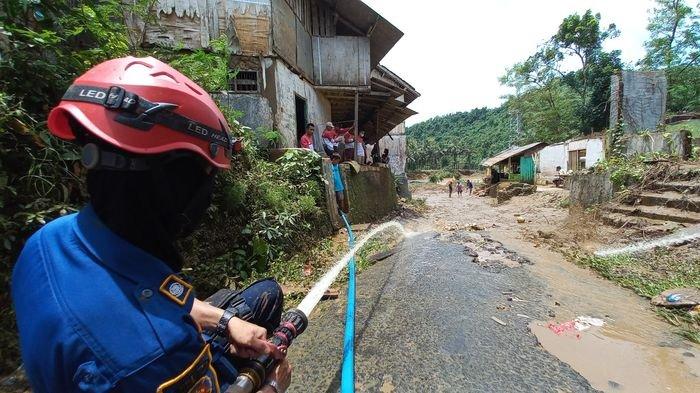 Petugas menyemprotkan air membersihkan jalan dari lumpur akibat banjir di Kampung Cinitih RT 08 RW 01 Desa Cibitung, Kecamatan Cibitung, Kabupaten Sukabumi, Jawa Barat, Sabtu (24/9/2022).