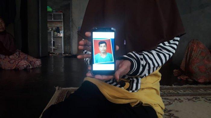 Amanah menunjukkan foto suaminya, Mamat Rahmat, yang menjadi korban jiwa banjir bandang Sumedang di kawasan Desa Citengah, Kamis lalu. Foto diambil Sabtu (27/3/2021).