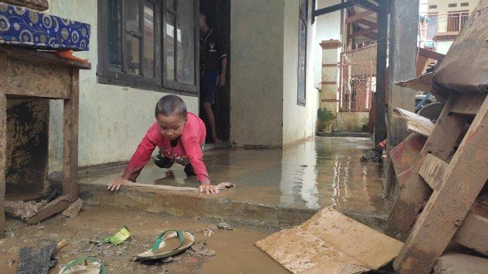 Seorang anak tengah membersihkan sisa-sisa lumpur akibat banjir bandang yang menerjang rumahnya di Kampung Munjul, Desa Sukawening, Kecamatan Sukawening, Kabupaten Garut (28/11/2021).