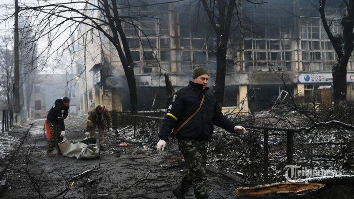 Petugas polisi mengeluarkan mayat seorang pejalan kaki yang tewas dalam serangan udara kemarin yang menghantam menara televisi utama Kyiv di Kyiv pada 2 Maret 2022. - Ukraina mengatakan pasukan Rusia menyerang rumah sakit jiwa di dekat kota Izyum.