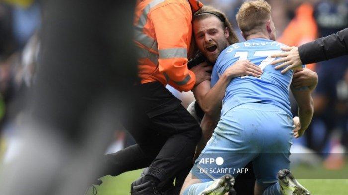 Gelandang Manchester City asal Belgia Kevin De Bruyne dipeluk oleh seorang penggemar yang menyerbu lapangan saat mereka merayakan kemenangan setelah memenangkan pertandingan sepak bola Liga Inggris antara Manchester City dan Aston Villa di Stadion Etihad di Manchester, barat laut Inggris, pada 22 Mei 2022. Manchester City mempertahankan gelar dan memenangkan Liga Premier Inggris.
