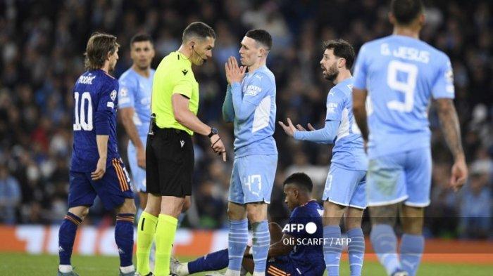 Gelandang Manchester City Inggris Phil Foden (tengah) dan gelandang Manchester City dari Portugal Bernardo Silva (kanan) berdebat dengan wasit Rumania Istvan Kovacs selama pertandingan sepak bola leg pertama semifinal Liga Champions antara Manchester City dan Real Madrid, di Stadion Etihad, di Manchester, pada 26 April 2022.