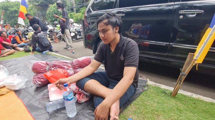 Ojek online, Rizky (20) (kaos hitam) duduk beralaskan terpal usai rumahnya di Jalan Simprug 2, RT 008 RW 008 Grogol Selatan, Kebayoran Lama, Jakarta Selatan terbakar pada Minggu (21/8/2022).