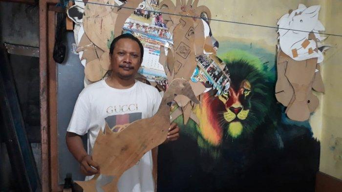 Sosok Hartono, pelukis spanduk pecel lele sedang memegang cetakan kardus berbentuk hewan untuk dilukis di spanduk pada Sabtu (20/2021).