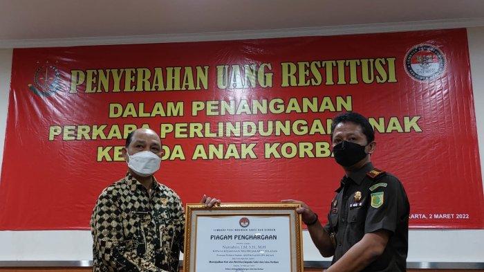 Kepala Kejaksaan Negeri Jakarta Selatan Nurcahyo (kanan) menerima penghargaan dari Wakil Ketua Lembaga Perlindungan Saksi dan Korban (LPSK) Antonius PS Wibowo setelah menyerahkan biaya ganti rugi (restitusi) bagi korban kasus perlindungan anak di Kantor Kejari Jakarta Selatan, Rabu (2/3/2022).