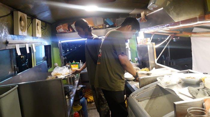 Dua karyawan Mie Aceh Kring-kring sedang memasak pesanan pengunjung di dalam dapur bus antik pada Senin (21/12/2020).