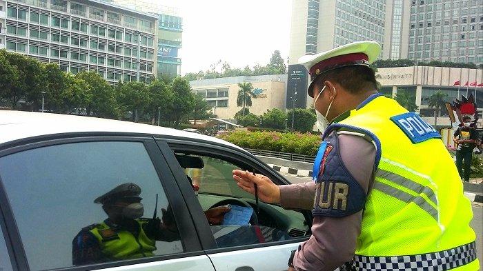 Kendaraan roda empat berwarna silver distop polisi lalu lintas karena melanggar kebijakan ganjil-genap kendaraan saat melintas di Jalan Sudirman, Jakarta Pusat, Senin (20/9/2021).