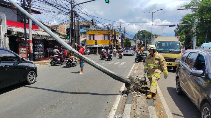 Personel Damkar Jakarta Timur saat proses penanganan tiang PJU yang roboh di Jalan Raya Bogor, Ciracas, Senin (24/10/2022)