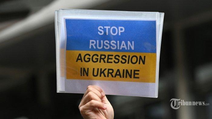 Seorang pengunjuk rasa mengangkat plakat selama demonstrasi menentang invasi Rusia ke Ukraina di Sydney pada 25 Februari 2022.