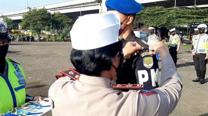 Operasi Keselamatan Jaya 2021 di kawasan Cawang, Jakarta Timur. Petugas membagikan brosur terkait tujuan kegiatan ini kepada pengendara, Senin (12/4/2021).
