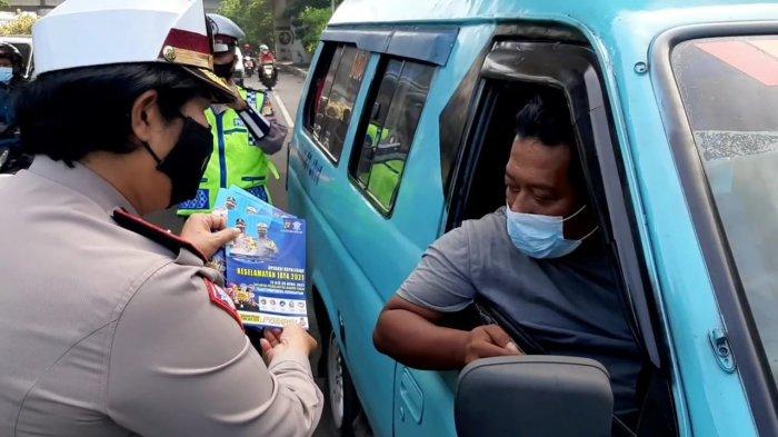 Operasi Keselamatan Jaya 2021 di kawasan Cawang, Jakarta Timur. Petugas membagikan brosur terkait tujuan kegiatan ini kepada pengendara, Senin (12/4/2021).