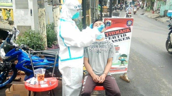 Petugas Puskesmas Pasar Rebo saat melakukan tes swab antigen terhadap pelanggar protokol kesehatan di Jalan Petigaan Gentong, Jakarta Timur, Jumat (8/1/2021)