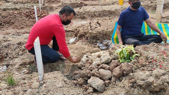 Peziarah di TPU Rorotan, Ahmad, merapikan makam ibunda yang ambles, Selasa (31/8/2021).
