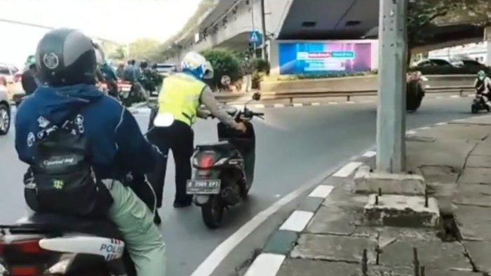 Polisi lalu lintas, Kanit Turjawali Satlantas Polres Jakarta Barat, AKP Karta membantu seorang perempuan yang mengalami kebocoran ban motor ke bengkel terdekat di kawasan Slipi, Grogol Petamburan, Jakarta Barat pada Kamis (3/11/2022).