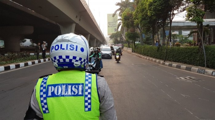 Petugas kepolisian memantau pengendara yang melanggar ganjil genap di simpang Pancoran, Jakarta Selatan, Rabu (18/7/2018). Pemberian bukti pelanggaran (tilang) bagi pelanggar mulai aktif berlaku pada 1 Agustus 2018.